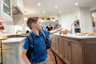Boy with backpack in kitchen