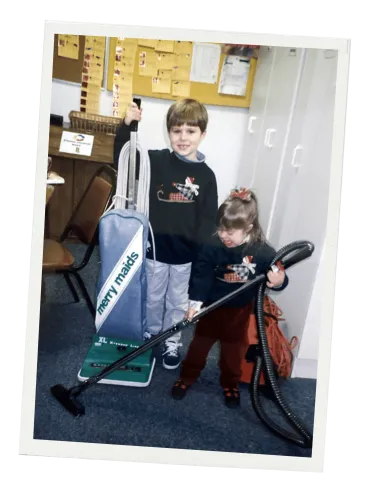 Drew Keller as a child posing with a Merry Maids vacuum at the original franchise location