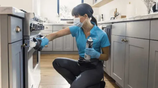 Merry Maids team member cleaning oven